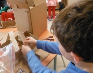 boy building roof trusses on cardboard model