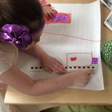 child measuring her drawing on grid paper