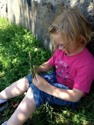 girl creating a tree using a stick and blades of glass