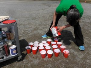 teacher pouring paint into solo cups
