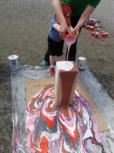 child pouring paint onto wooden tower